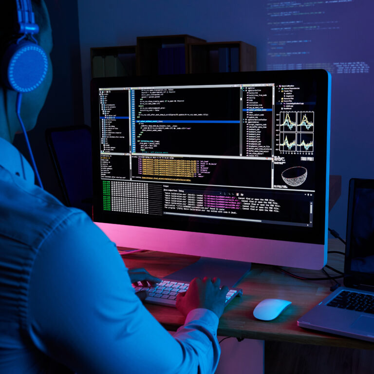 Programmer in headphones checking his code on computer screen